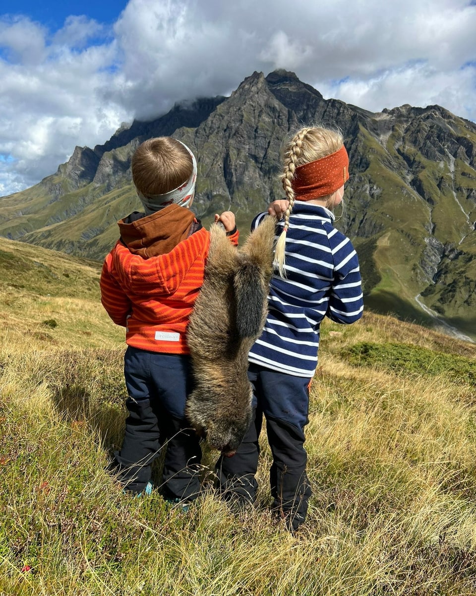 Foto da dus uffants che portan ina muntanella.