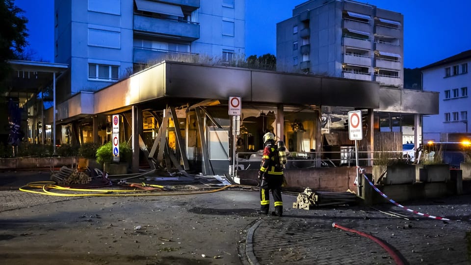 Feuerwehrmann vor zerstörtem Gebäude bei Nacht.