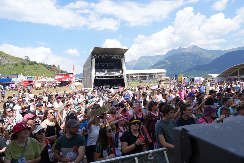 Menschenmenge auf einem Open-Air-Konzert vor einer Bühne in den Bergen am Open Air Lumnezia 2024.