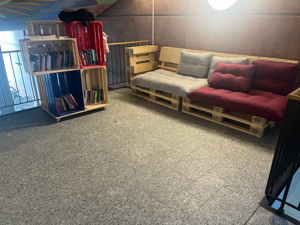 Palettensofa und Bücherregale in einer Lounge-Ecke.