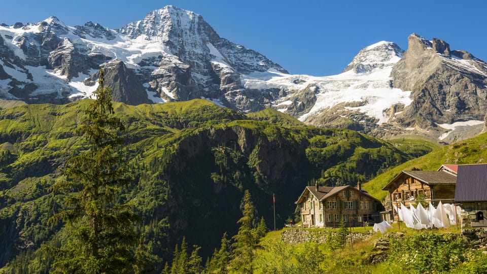 Berglandschaft mit Schneebedeckten Gipfeln und Häusern im Vordergrund.