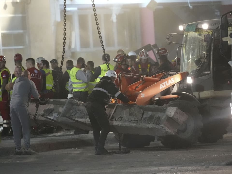 Rettungskräfte heben Betonplatte mit Bagger an Unglücksstelle.