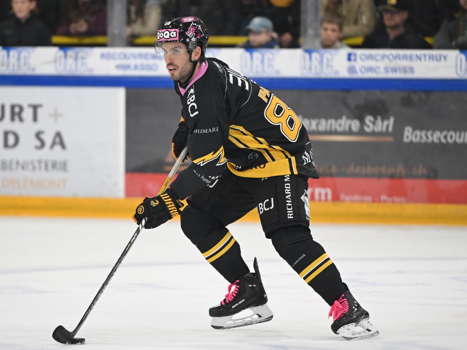 Eishockeyspieler in schwarzer Ausrüstung beim Spiel.