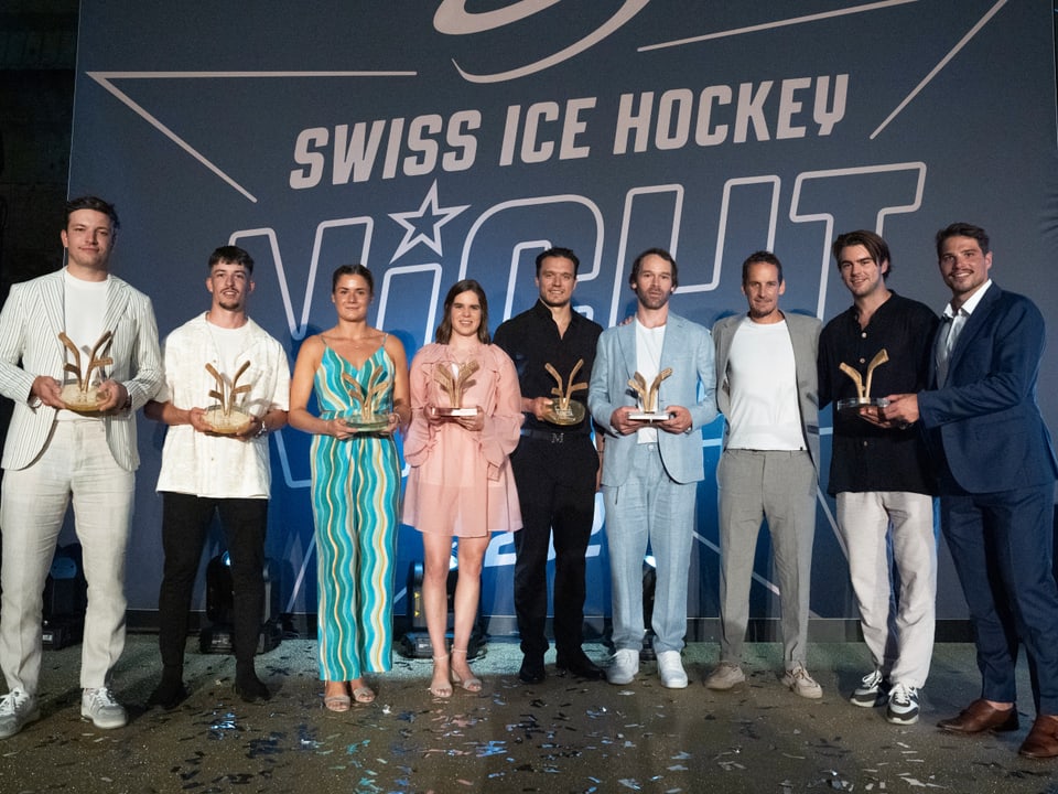 Gruppe von Menschen hält Trophäen bei Swiss Ice Hockey Nacht.