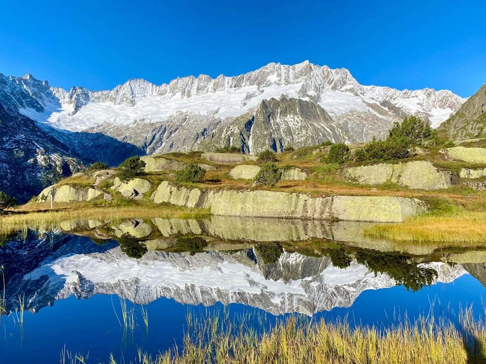 Berge im Hintergrund, die sich in einem Bergsee spiegeln.