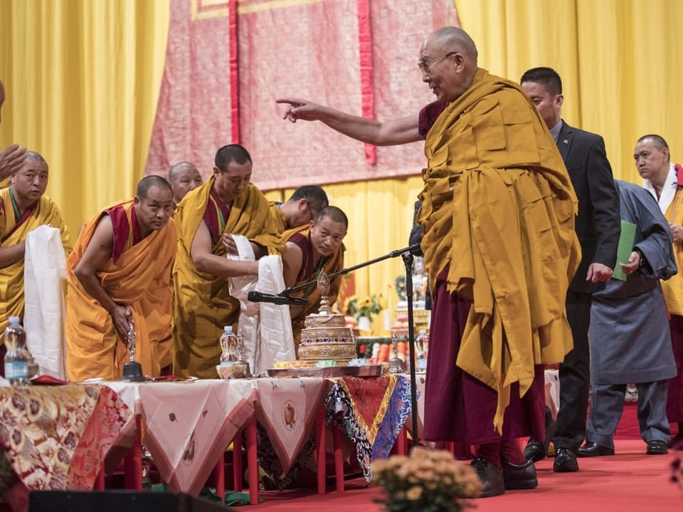 Dalai Lama streckt seine Hand über Männer