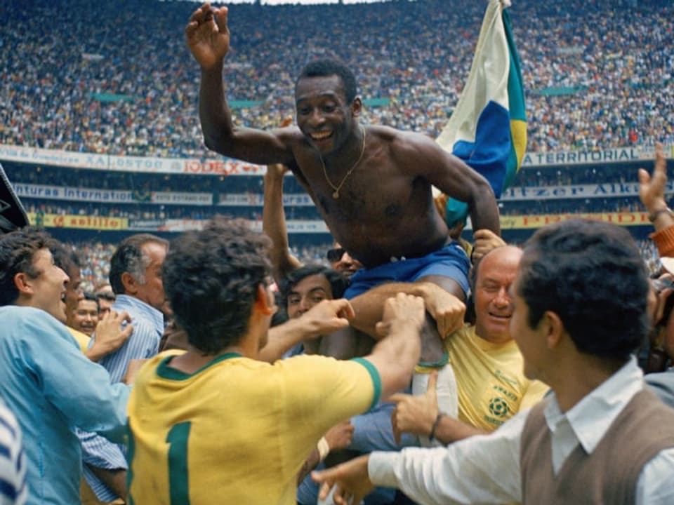 Ein junger Pelé wird von seinem Fussballteam in die Höhe gehalten.