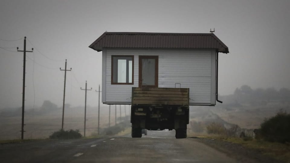 Unglaubliches Bild: Ein Lastwagen trägt ein kleines Haus auf seiner Ladefläche und fährt auf einer Strasse davon.
