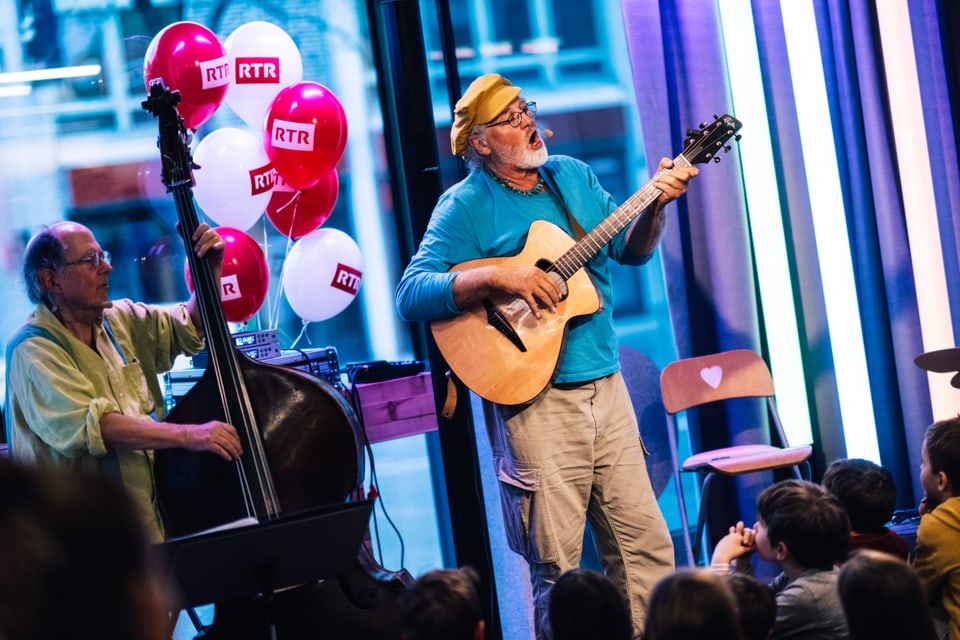 Zwei Musiker spielen live vor Publikum mit Gitarre und Kontrabass, Luftballons im Hintergrund.