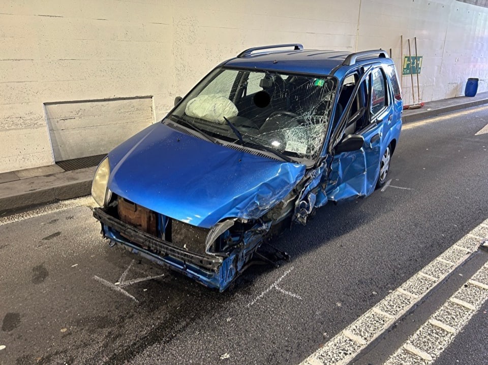 Blauer Kleinwagen mit schweren Frontschäden in einem Tunnel.