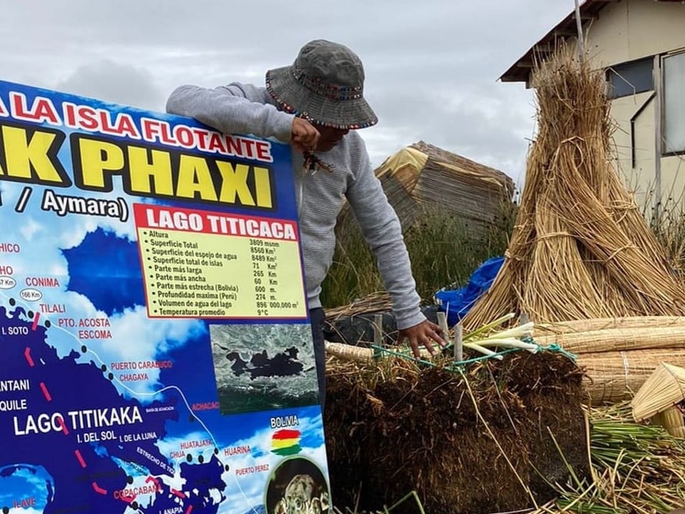 Person verbindet Schilfrohr neben Schild von Lago Titicaca.