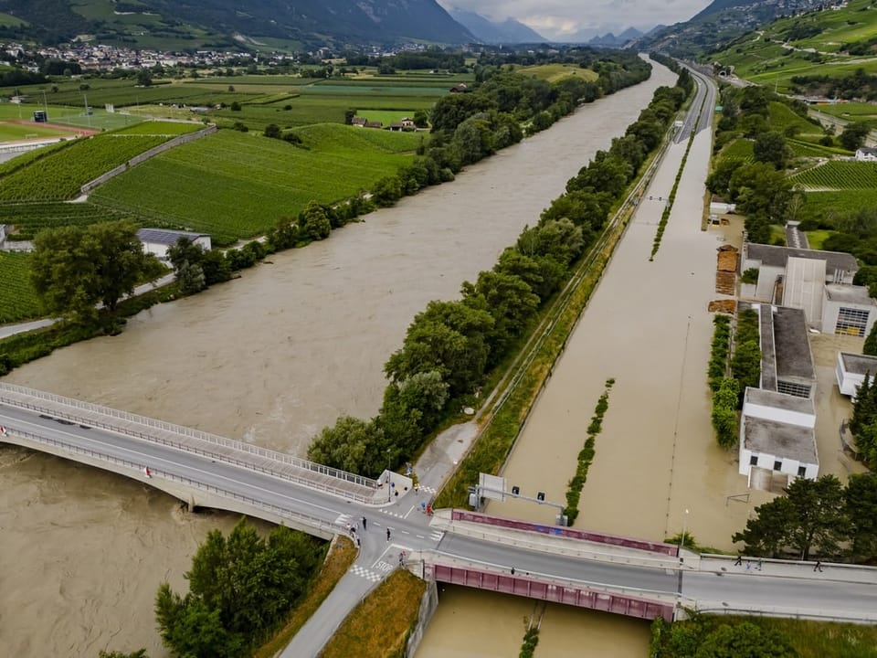 Luftaufnahme von Hochwasser in einer Flusslandschaft mit Brücken und Gebäuden.
