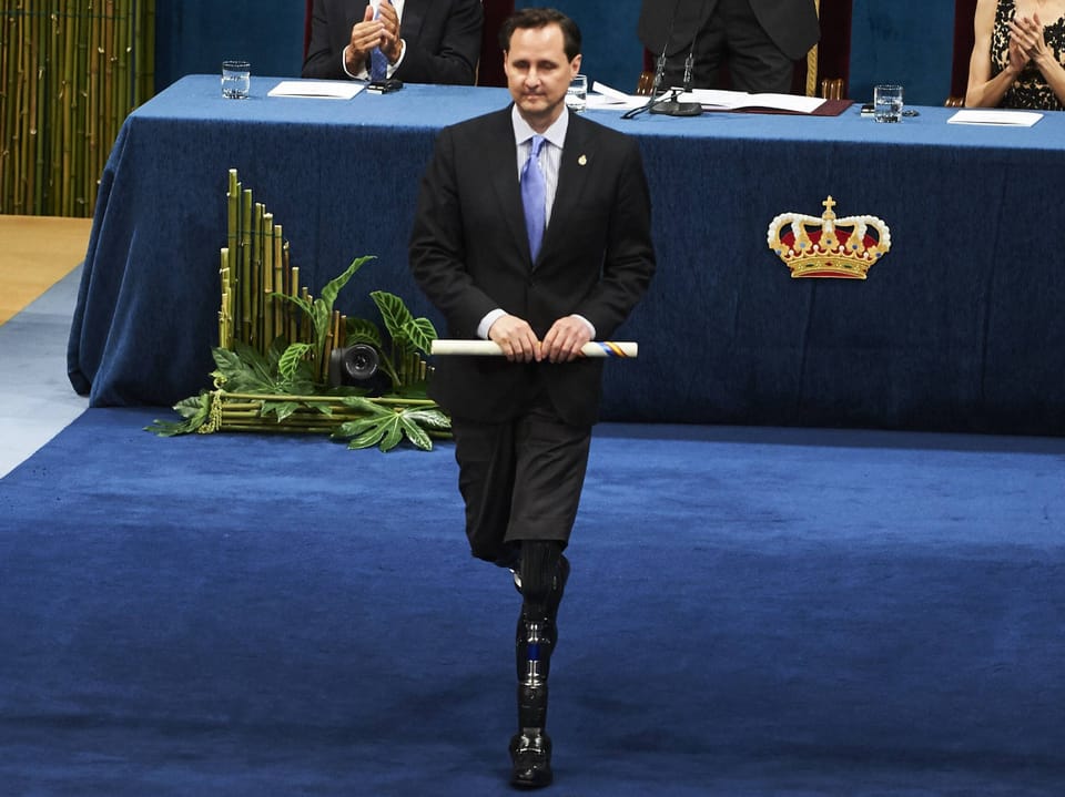 Person hält einen Preis in der Hand und läuft mit zwei Beinprothesen.