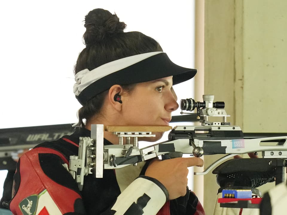 Frau zielt mit einem Sportschützengewehr.