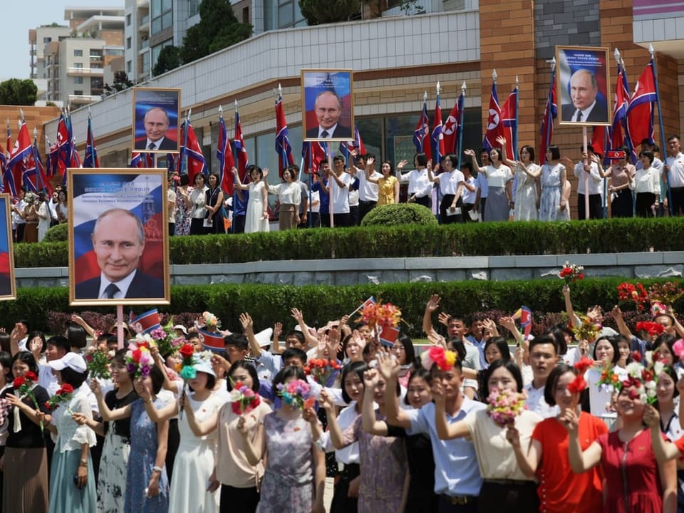 Menschen jubeln mit Plakaten von Putin. 