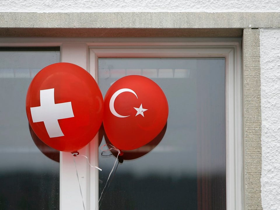 Zwei Ballöne mit der Schweizer und der türkischen Flagge an einem Fenster