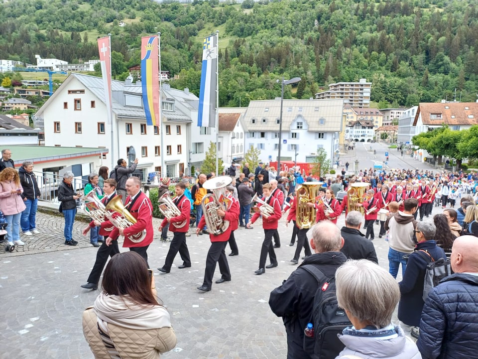 Blaskapellenumzug im Dorf, Zuschauer am Strassenrand.