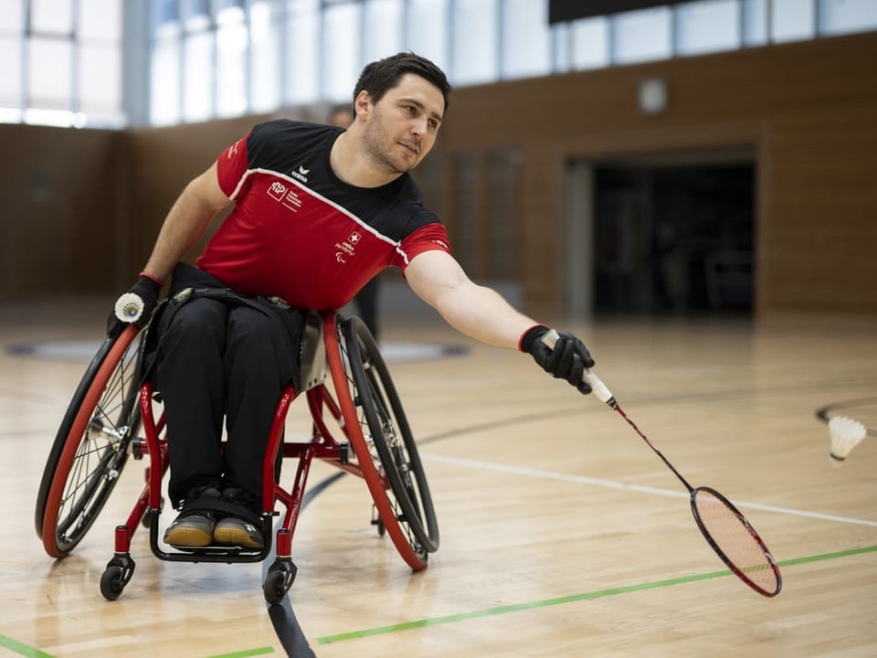 Rollstuhlfahrer beim Badmintonspiel in der Sporthalle.