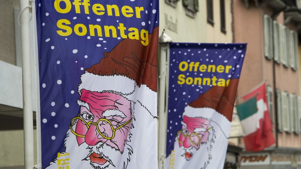 Zwei Fahnen mit dem Slogan «Offener Sonntag» und dem Bild des Samichlaus weisenauf den verkaufsoffenen Sonntag hin. 