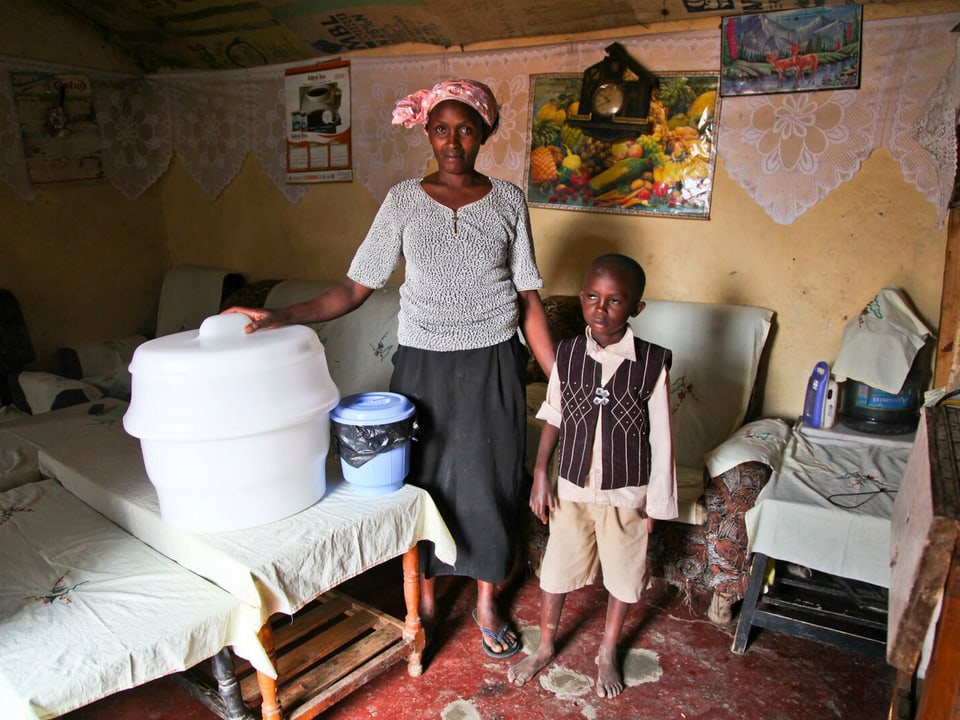 Eine Hütte in Naivasha, Kenia: Eine Frau posiert mit einem Jungen neben einem mobilen Klo.