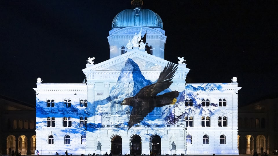 Ein Adler auf Berglandschaft wird auf das Bundeshaus projieziert.