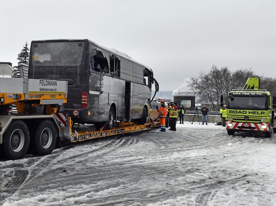 Abschleppen eines beschädigten Busses durch einen Abschleppwagen im Schnee.