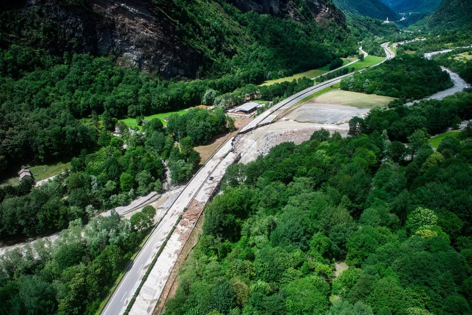 Luftaufnahme einer Strasse durch bewaldete Berge.