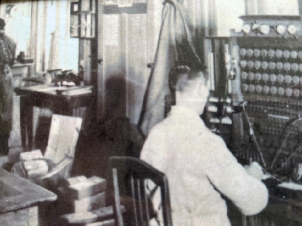 Person in historischer Telefonzentrale arbeitend.