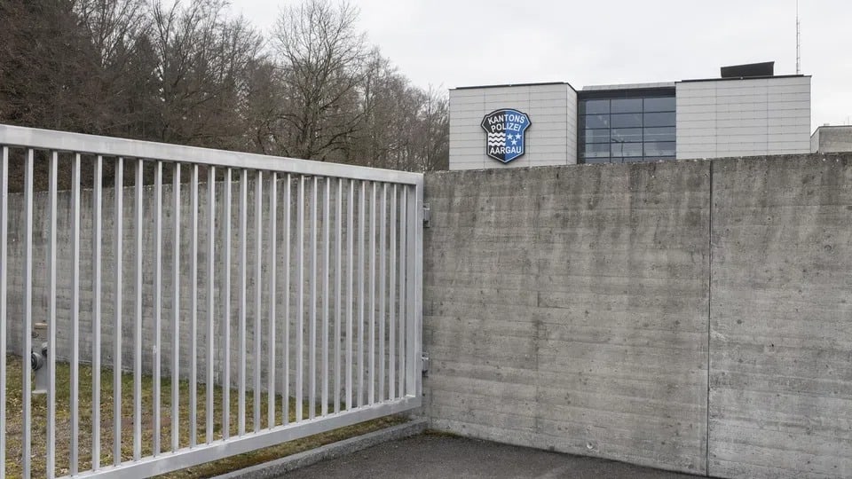 Eine Betonmauer, dahinter ein modernes, graues Gebäud der Kantonspolizei Aargau.