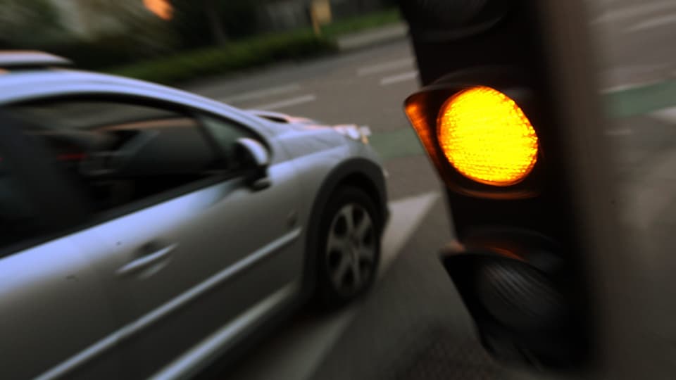 Ein Auto fährt über ein oranges Lichtsignal.