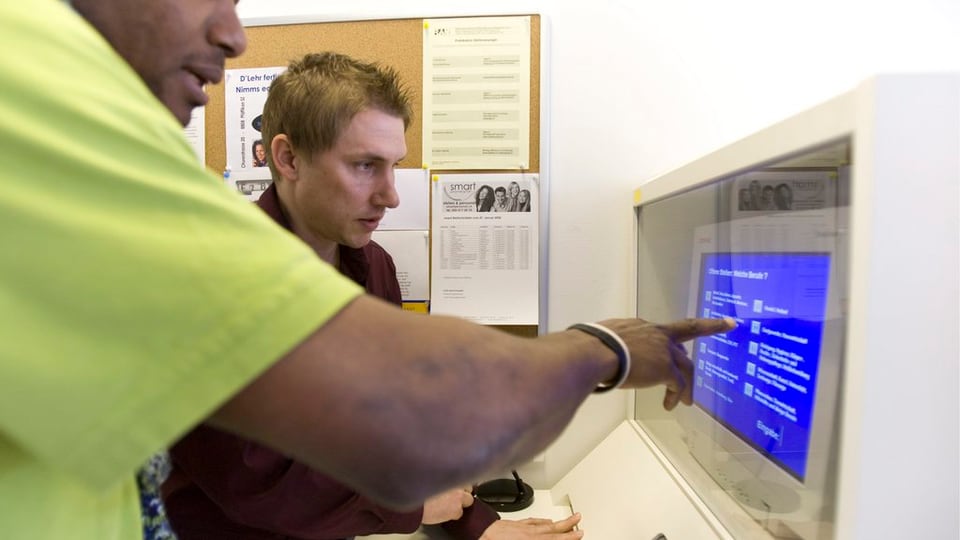 Zwei Männer stehen vor einem Computer.