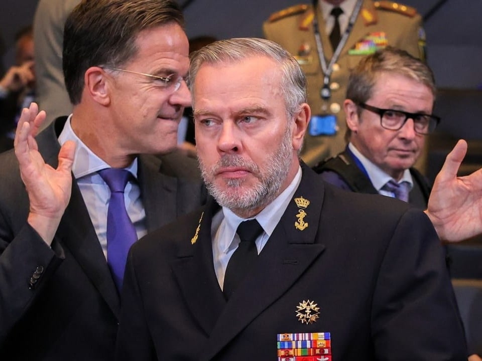 Männer in Anzügen und Uniform in Diskussion.