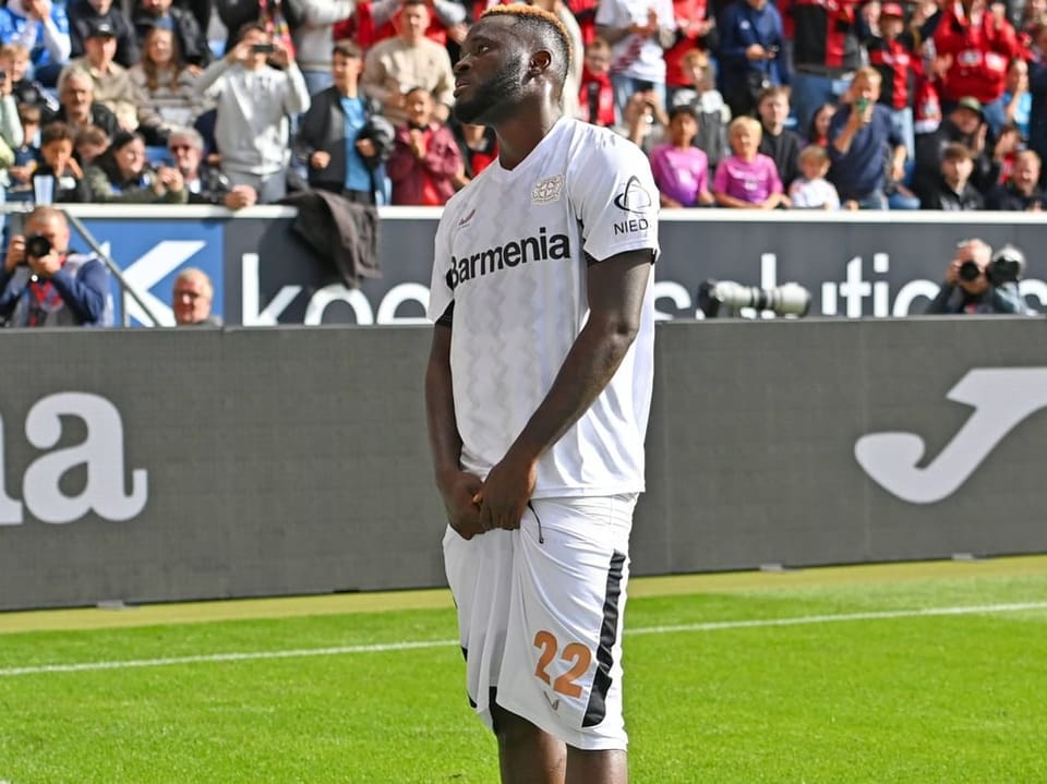 Fussballspieler im weissen Trikot vor Stadionpublikum.