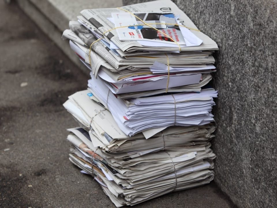 Gestapeltes Bündel alter Zeitungen und Papiere auf dem Bürgersteig.