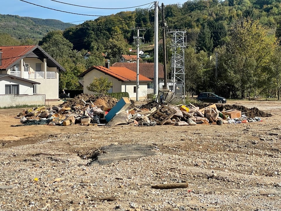 Haufen von Schutt und Abfall vor Häusern in ländlicher Gegend.