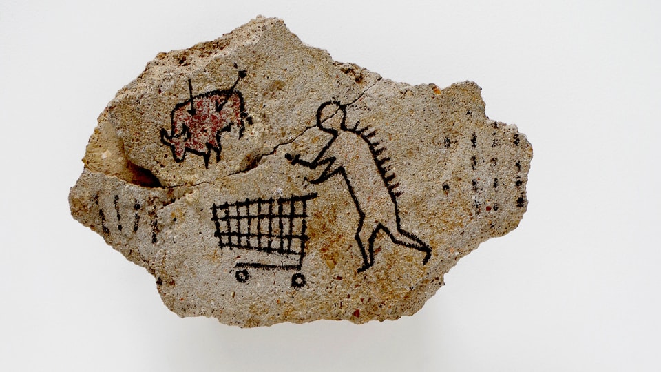 Ein Stein mit einer Strichfigur, die einen Einkaufswagen schiebt.