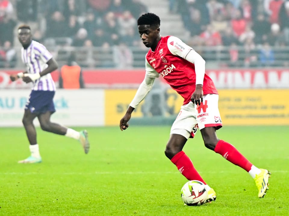 Fussballspieler im roten Trikot mit dem Ball.