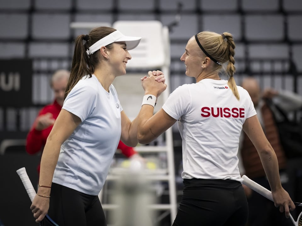 Zwei Tennisspielerinnen geben sich die Hand auf dem Platz.