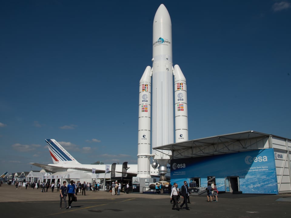 Rakete des Typs Ariane 5 vor einem Passagierflugzeug