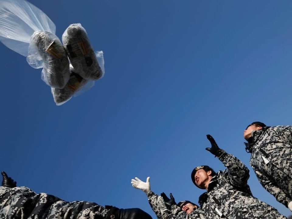 Soldaten werfen Pakete in den Himmel.