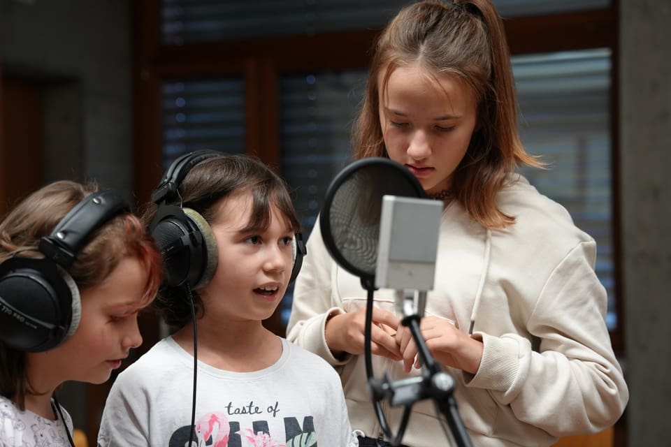 Drei Mädchen singen in ein Mikrofon im Aufnahmestudio.