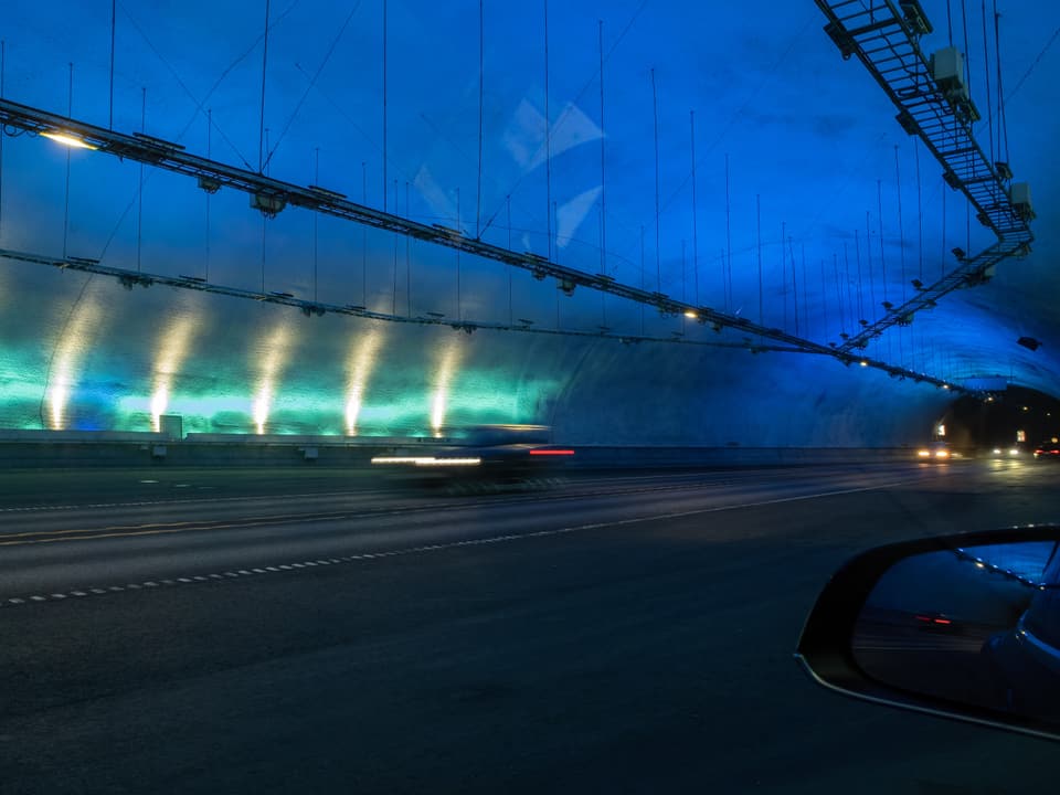 Fahrbahn in einem beleuchteten Tunnel bei Nacht.