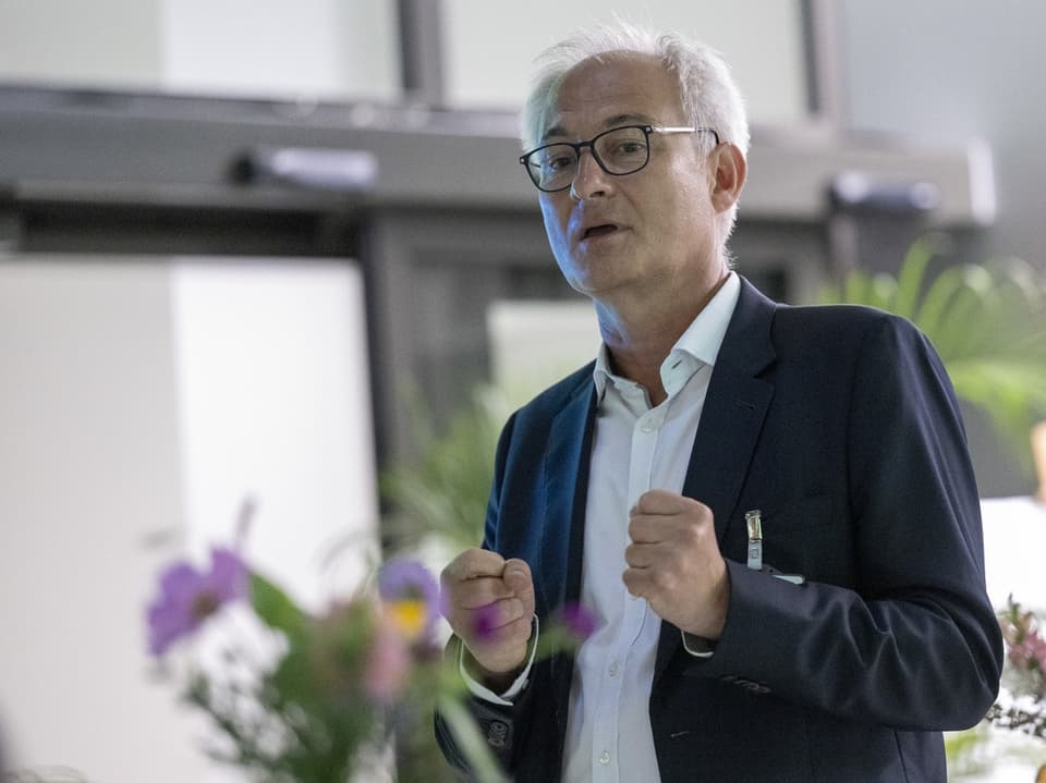 Bernhard Pulver mit Brille und dunkelblauem Blazer, die Hände zu Fäusten geballt. 