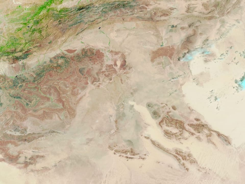 Satellitenbild einer Wüstenlandschaft mit grünen und braunen Bereichen.