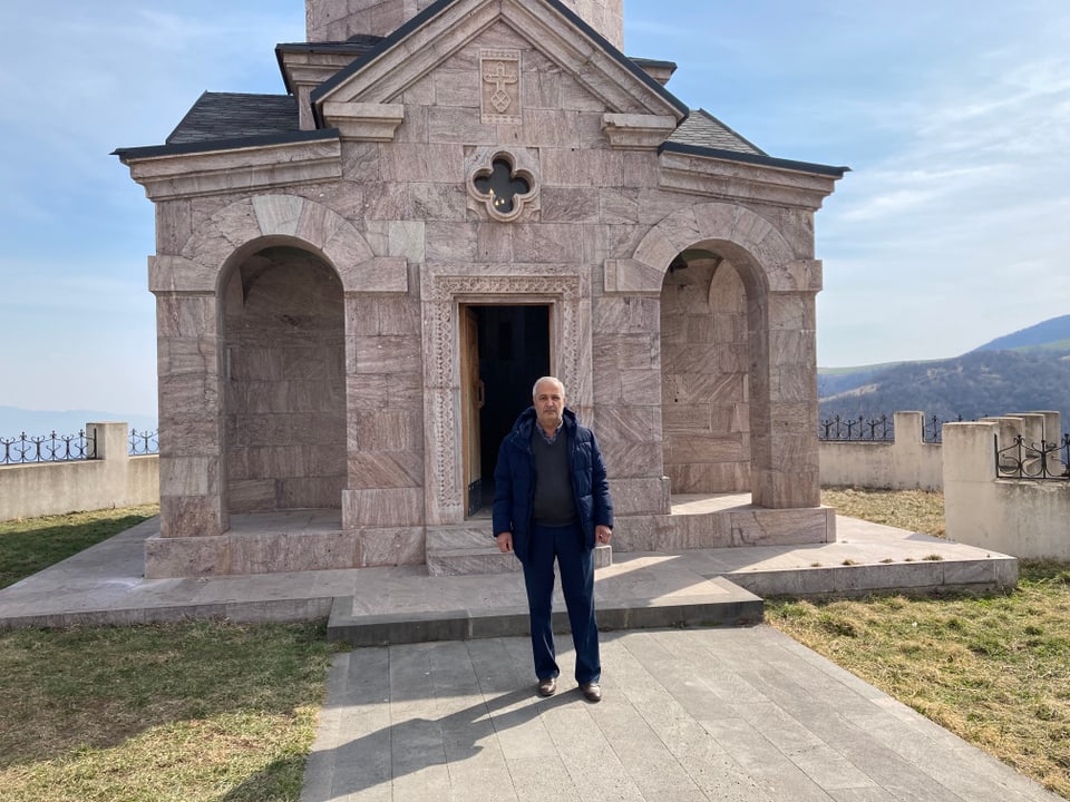 Ein Mann steht vor einer kleinen Kirche