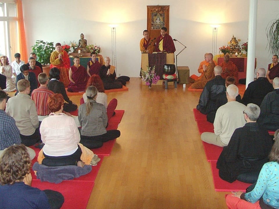 Menschen sitzen in einer Meditationsgruppe und lauschen einem Vortrag.