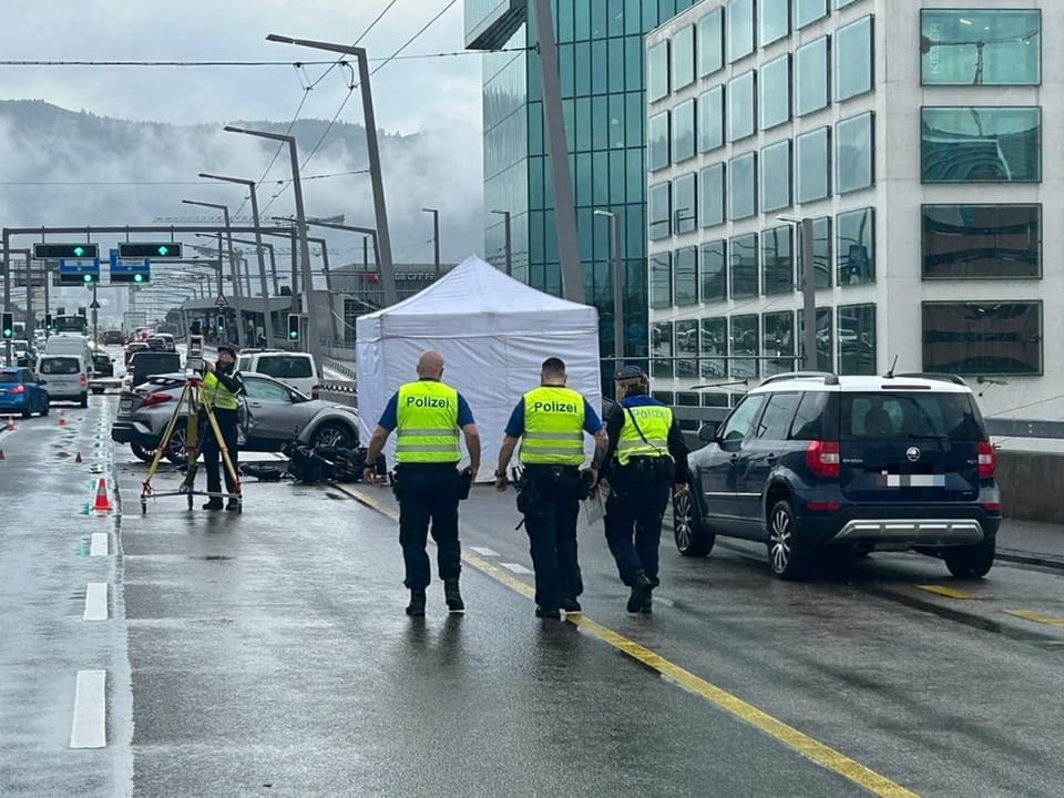 Polizei untersucht Unfallstelle auf regennasser Strasse.