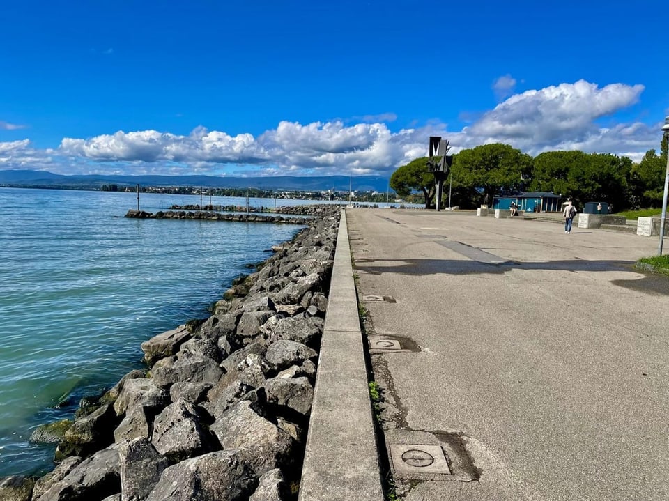 Promenade am See mit blauem Himmel und Wolken.