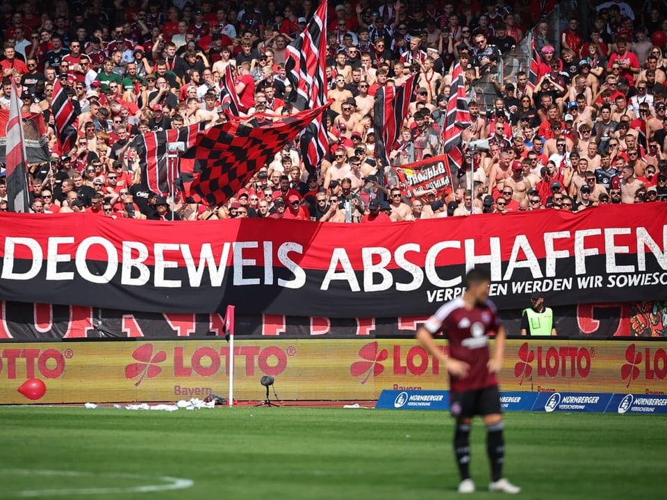 Fussballfans halten ein Banner mit der Aufschrift 'VIDEOBEWEIS ABSCHAFFEN' im Stadion.