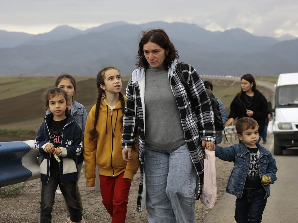 Eine Mutter und ihre Kinder schreiten auf einer Strasse voran.